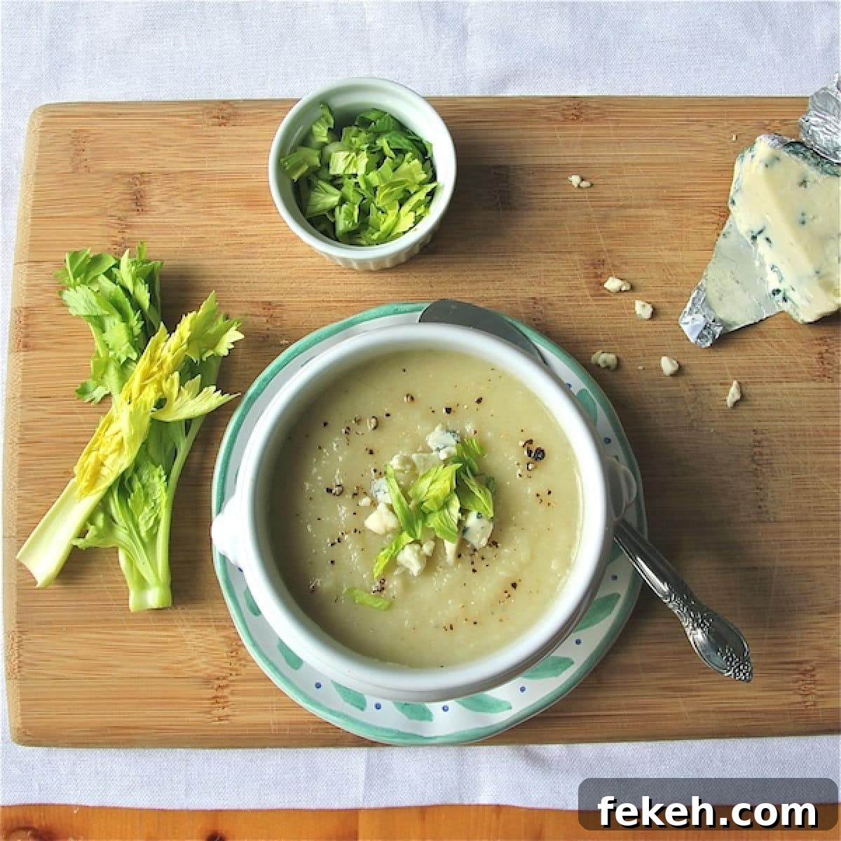 Celery Root Soup with Leek Confit and Gorgonzola - 600 A bowl of celery root soup, topped with celery tops, gorgonzola cheese and ground black pepper.