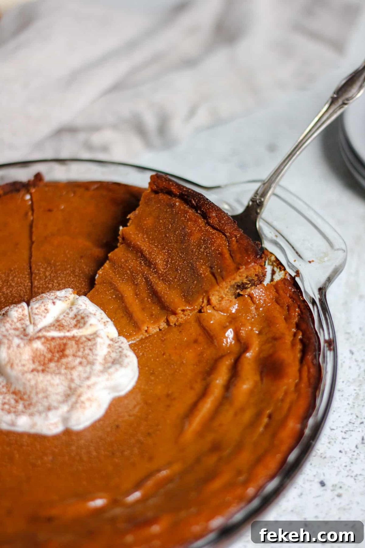 serving a slice of pumpkin pie from a glass dish
