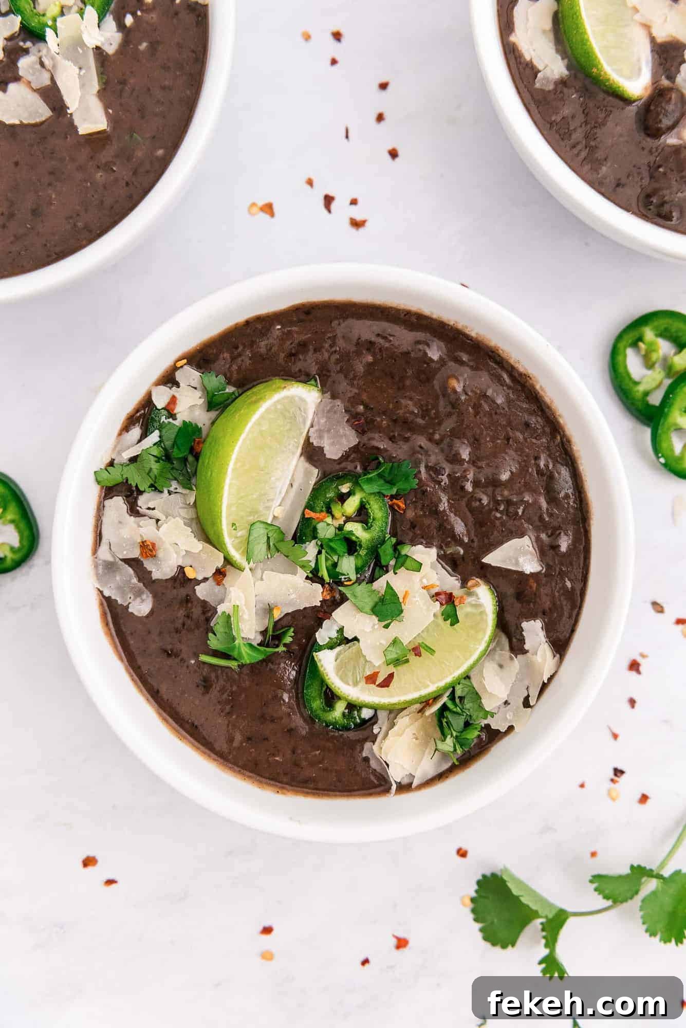 Instant Pot Black Bean Soup with Soaked or Dry Beans 2 Overhead view of a bowl of black bean soup with garnishes including lime wedges.