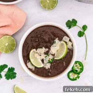 Instant Pot Black Bean Soup with Soaked or Dry Beans 16 Overhead view of a bowl of black bean soup garnished with lime slices and jalapeno.