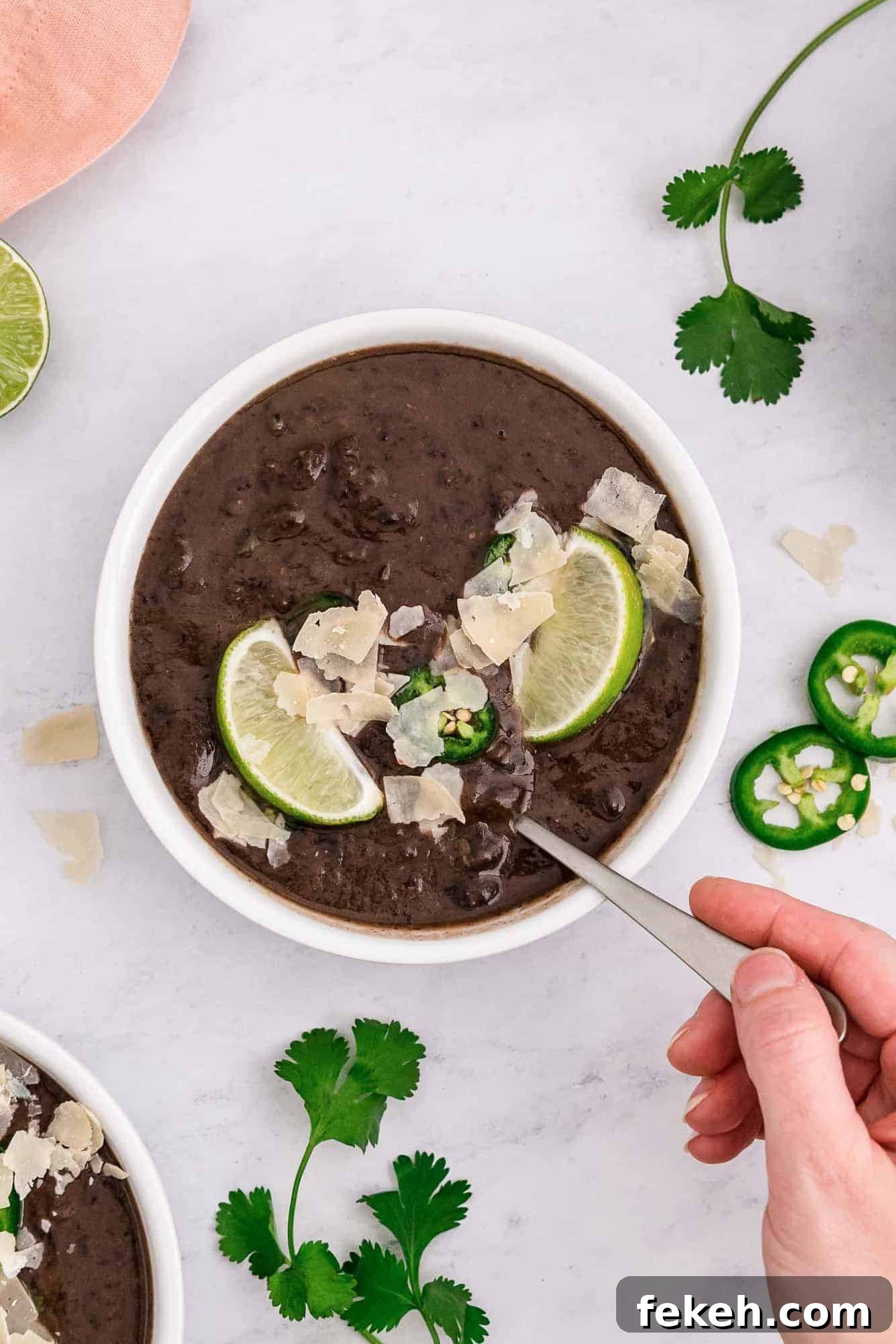 Instant Pot Black Bean Soup with Soaked or Dry Beans 9 A hand holding a spoon in a bowl of soup.