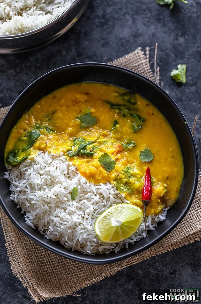 dal and rice in a black bowl with a red chili and lime wedge