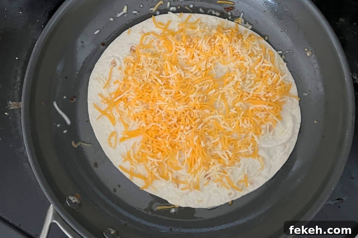 Applebee's Chicken Fajita Roll-Up Copycat Recipe 5 Cheese melting on a tortilla in a pan.