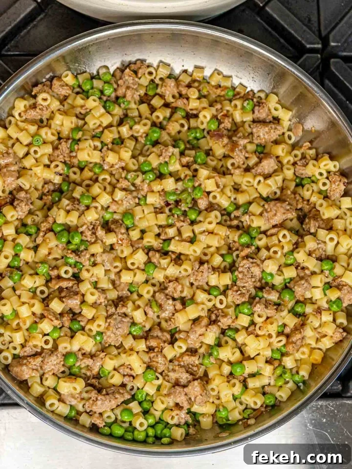 Ditalini Pasta with Italian Sausage and Peas 8 Ditalini pasta fully tossed with crumbled sausage and peas in a stainless steel skillet.