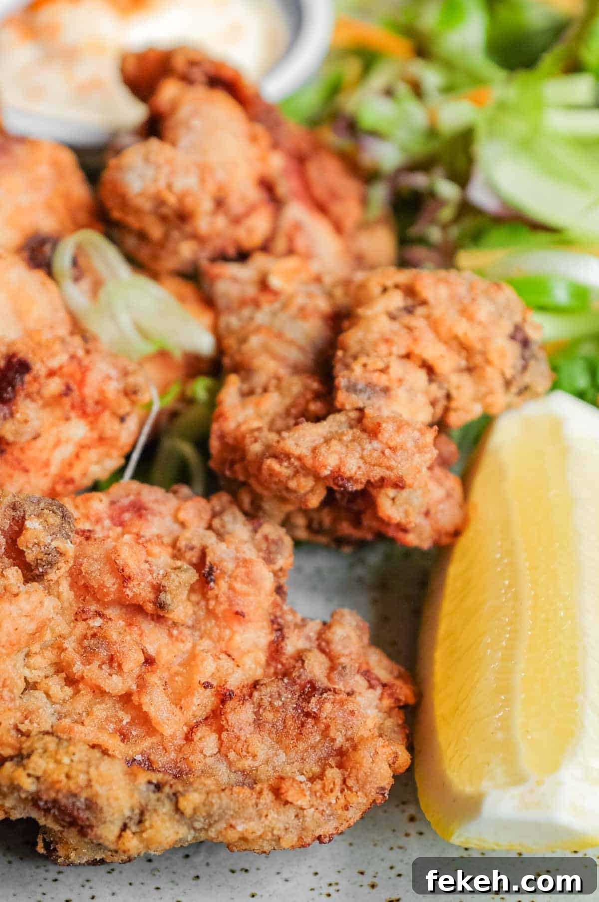 A plate of Japennese karaage chicken with a side salad, lemon wedge, and mayonnaise