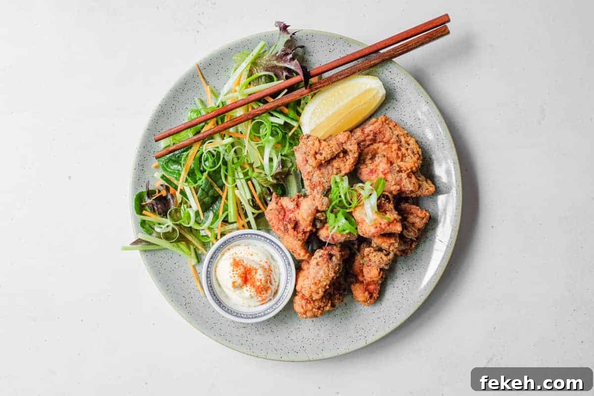 A plate of Japennese karaage chicken with a side salad, lemon wedge, and mayonnaise