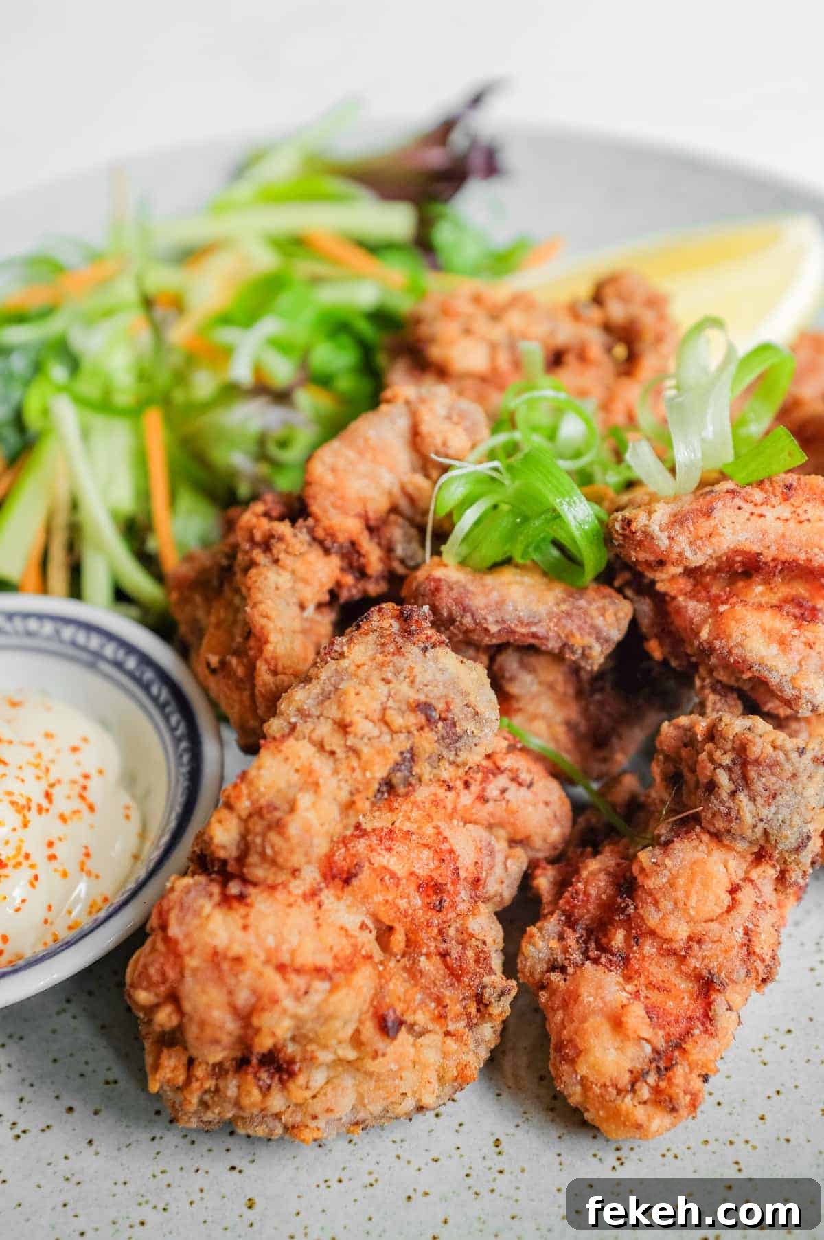 A plate of Japennese karaage chicken with a side salad, lemon wedge, and mayonnaise