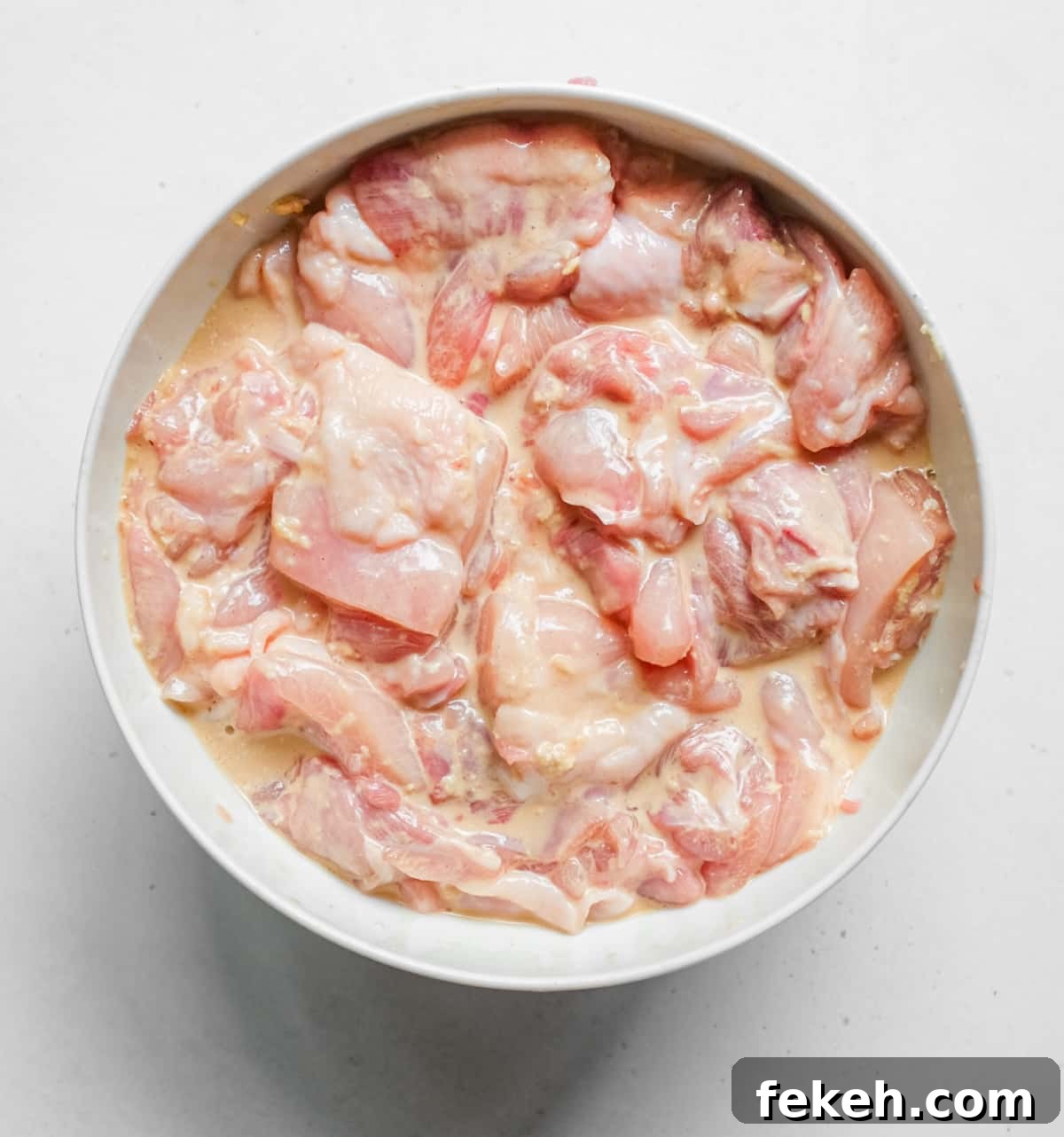 Chicken pieces sit in the special marinade for Karaage fried chicken.