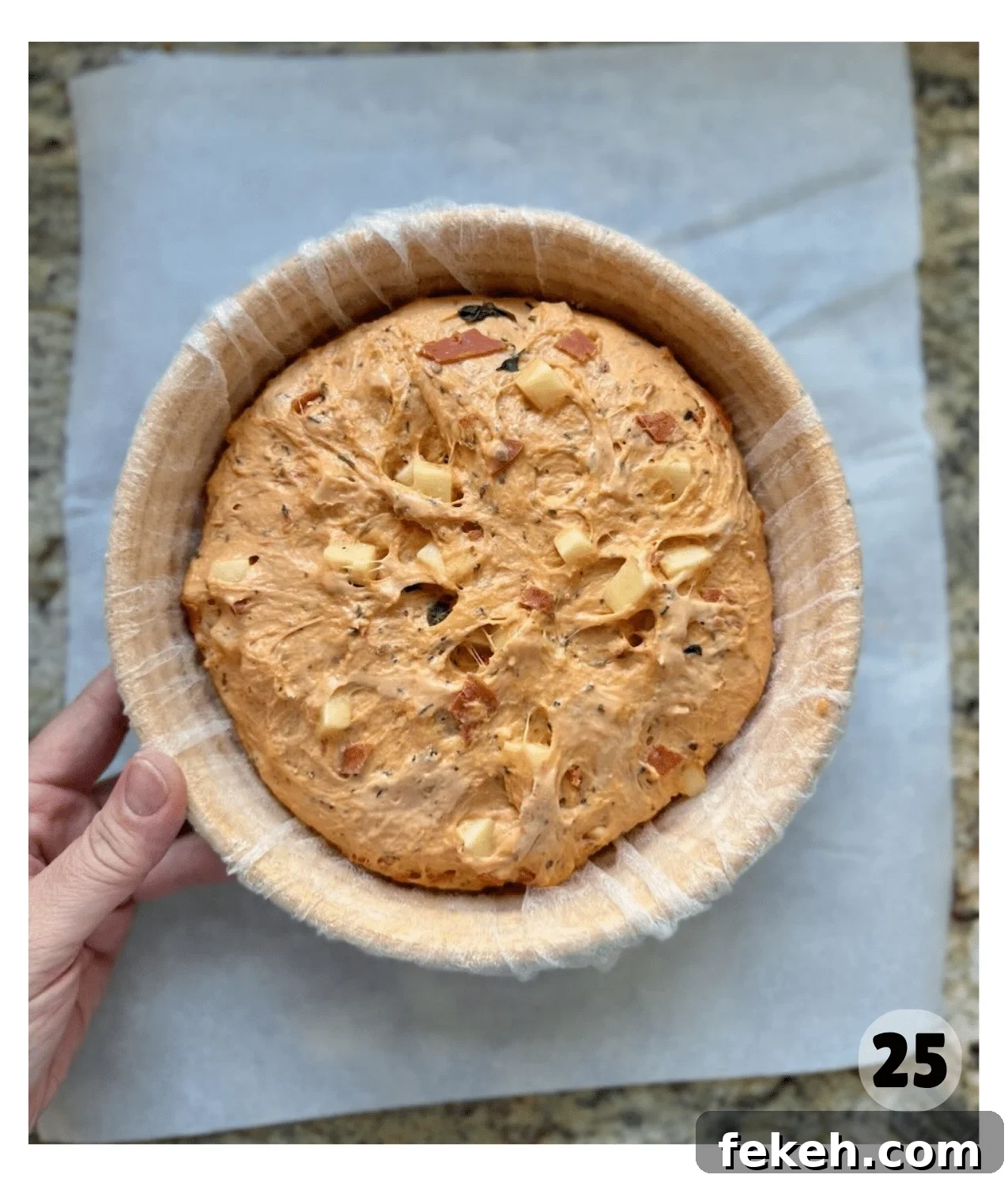 Sourdough Pizza Bread Recipe for Crispy, Flavorful Crust 14 Proofed dough in a banneton basket is risen and chunks of mozzarella, basil, and pepperoni are visible on the surface.