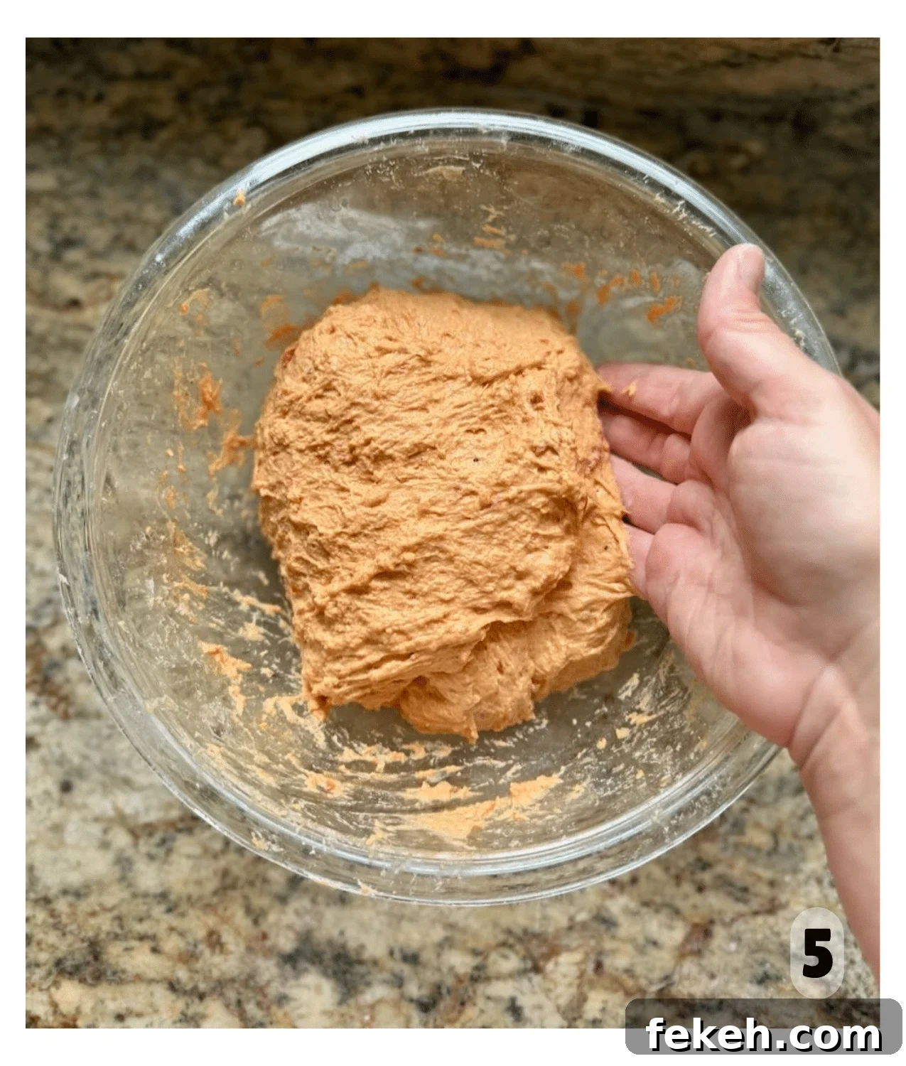 Sourdough Pizza Bread Recipe for Crispy, Flavorful Crust 7 A hand gently touches the side of a mixed but sticky looking ball of dough in a mixing bowl.