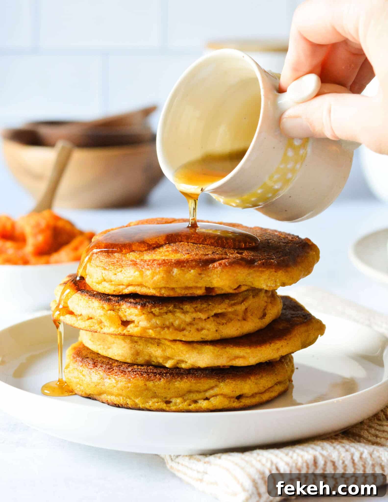 Gluten-Free Pumpkin Pancakes Recipe for Fluffy Fall Mornings 2 pouring maple syrup onto a stack of pumpkin pancakes.
