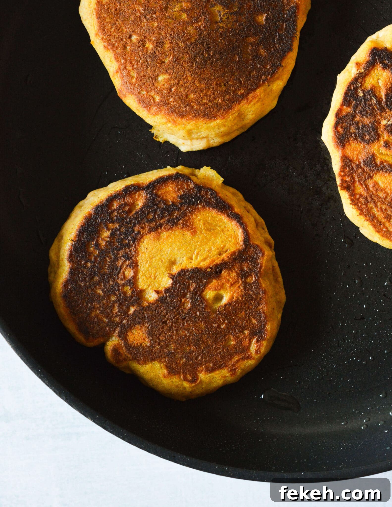 Gluten-Free Pumpkin Pancakes Recipe for Fluffy Fall Mornings 10 gluten free pumpkin pancakes in a skillet.