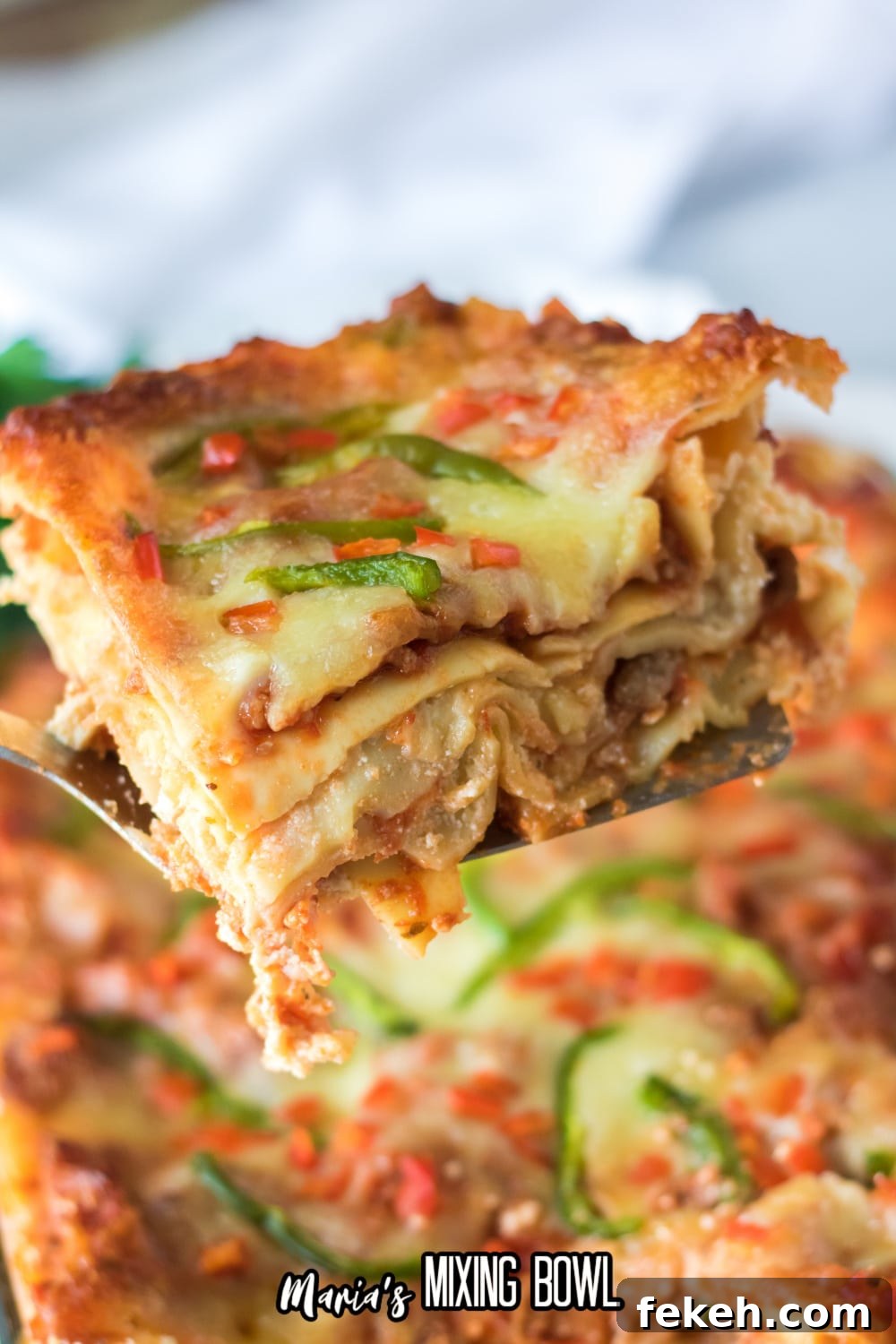 slice of christmas lasagna being held on a metal spatula in the air