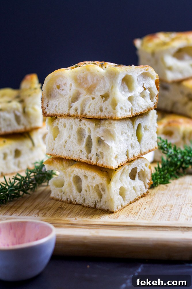 Crispy Sourdough Focaccia Recipe for Flavorful Homemade Bread 4 rosemary sourdough focaccia on cutting board with rosemary sprigs and pink bowl