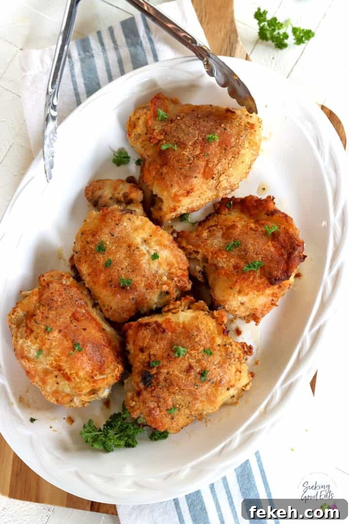 Southern-Style Oven-Baked Chicken Thighs Recipe 2 Five golden crispy baked chicken thighs served on a white platter.
