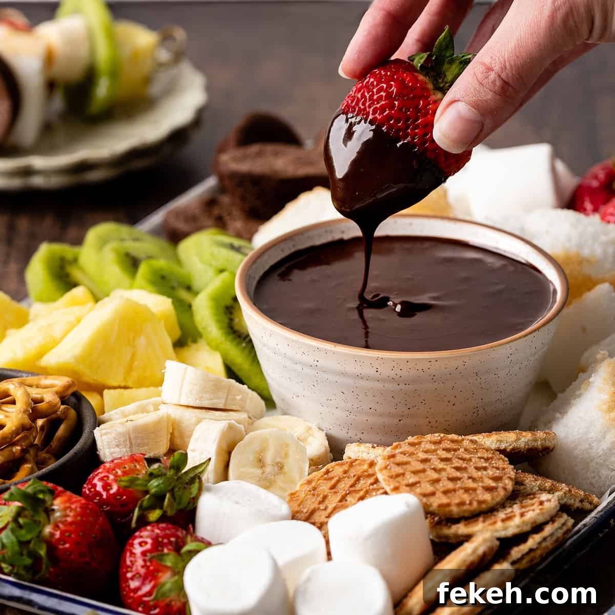 Decadent Chocolate Fondue Recipe for Dipping Fruit & Treats 2 a strawberry being dipped into Chocolate Fondue