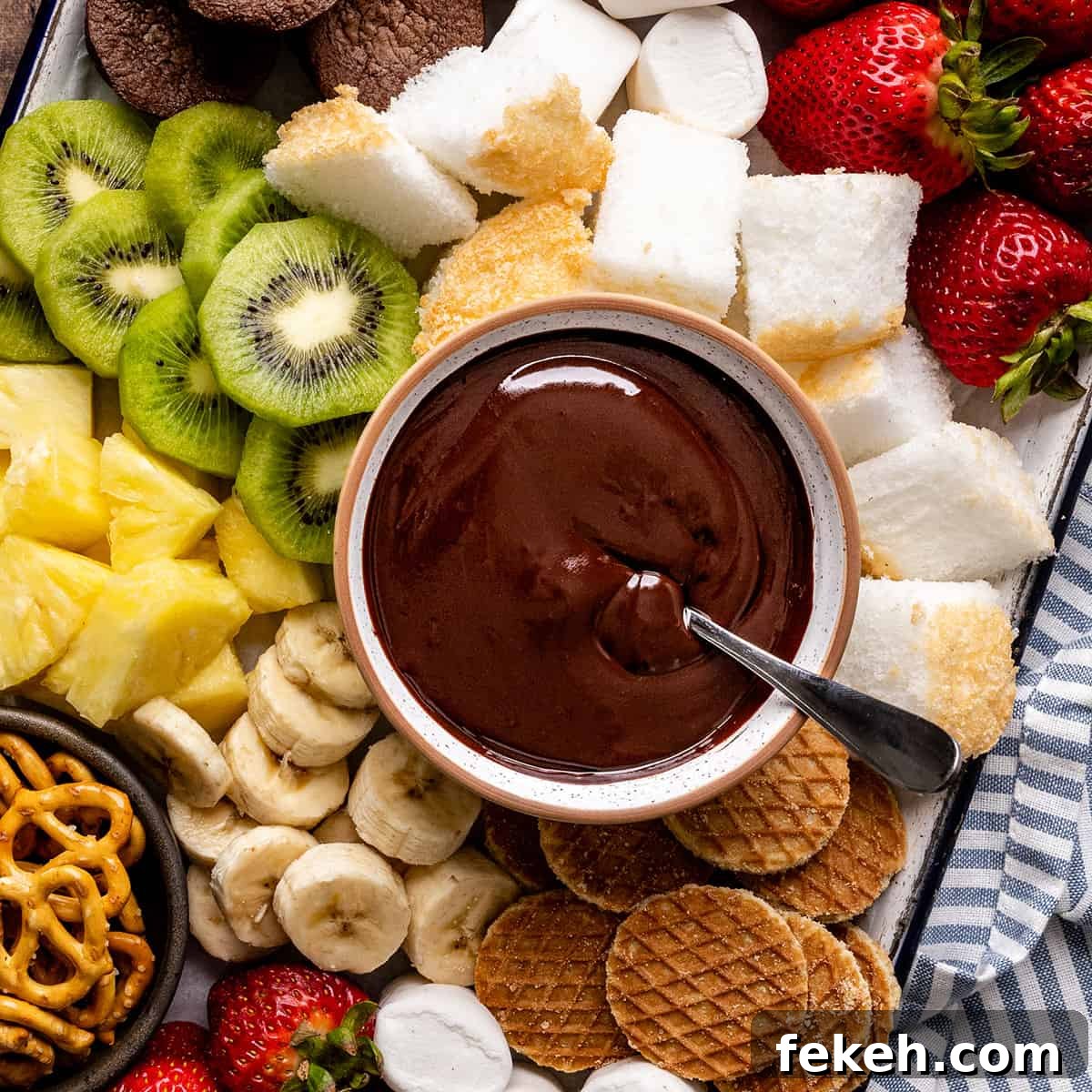 Decadent Chocolate Fondue Recipe for Dipping Fruit & Treats 3 overhead view of a bowl of Chocolate Fondue surrounded by chocolate fondue dippers