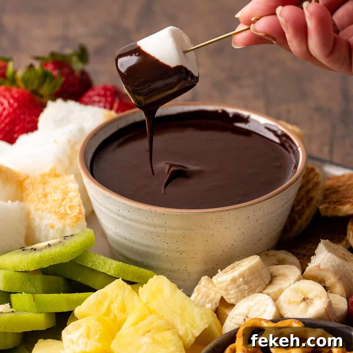 Decadent Chocolate Fondue Recipe for Dipping Fruit & Treats 9 a marshmallow being dipped into a bowl of Chocolate Fondue