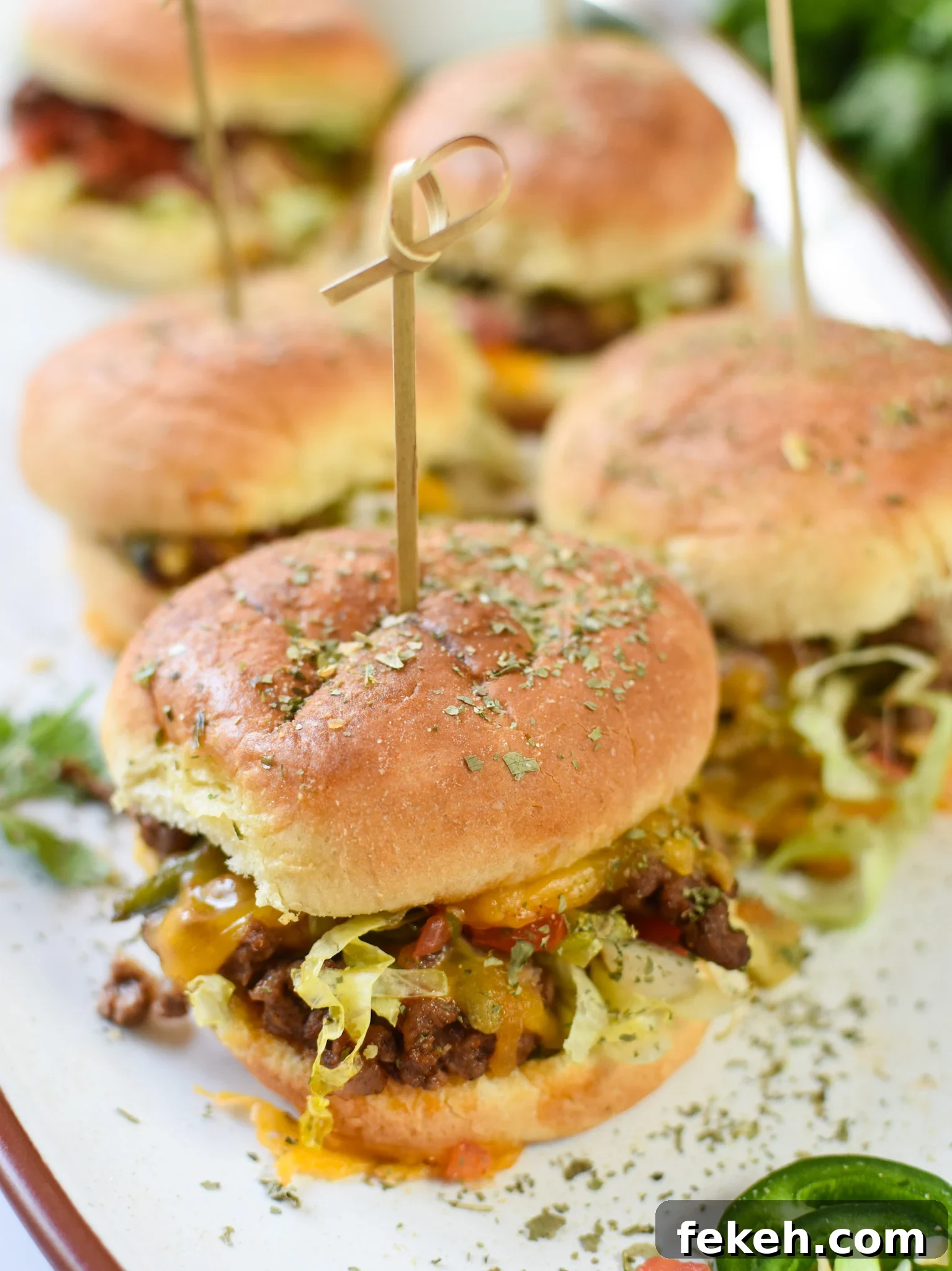 Taco Beef Sliders: Quick Party Sliders with Spicy Beef & Cheese 3 Taco Beef Sliders on a white platter.