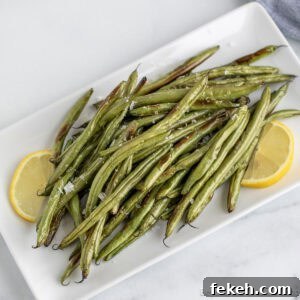 Crispy Oven-Roasted Green Beans with Garlic and Parmesan 11 Oven Roasted Green Beans on a white platter with lemon slices.