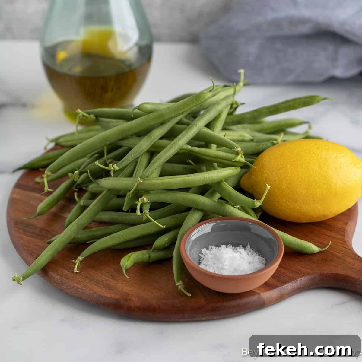 Crispy Oven-Roasted Green Beans with Garlic and Parmesan 3 Fresh green beans on a board with a fresh lemon and a small bowl of salt.
