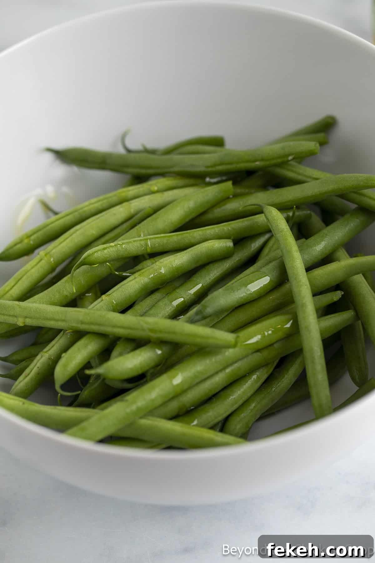 Crispy Oven-Roasted Green Beans with Garlic and Parmesan 4 Fresh green beans in a white bowl.