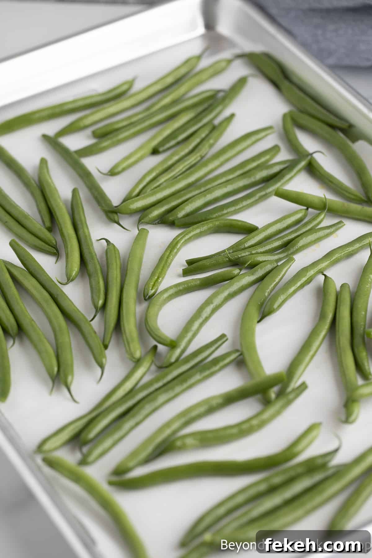 Crispy Oven-Roasted Green Beans with Garlic and Parmesan 5 Green beans on a baking sheet lined with parchment paper.