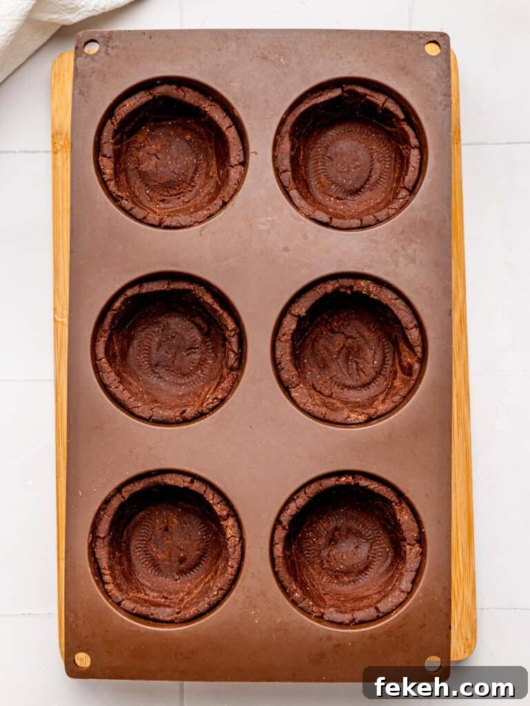 No-Bake Mini Triple Chocolate Cheesecakes Recipe 12 Mini No Bake Chocolate Cheesecake Crust pressed into muffin tray cavities.