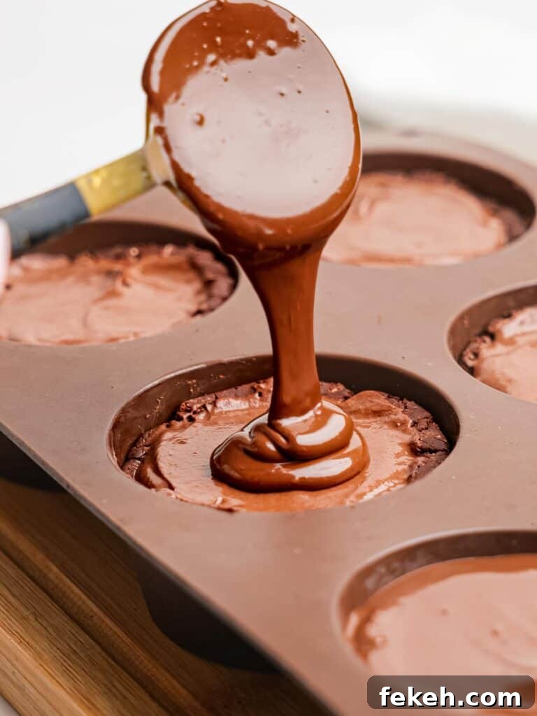 No-Bake Mini Triple Chocolate Cheesecakes Recipe 17 Pouring melted dark chocolate onto mini chocolate cheesecakes.