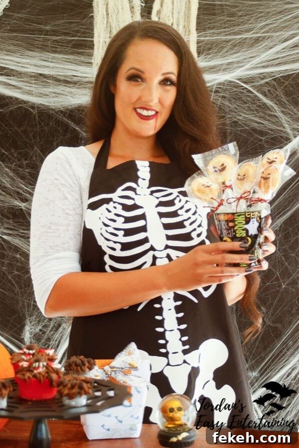 Jack-o'-Lantern Pumpkin Pie Pops Recipe for Halloween Treats 2 Jordan from Jordan's Easy Entertaining holding up jack-o-lantern pumpkin pie pops with a spooky spiderweb background