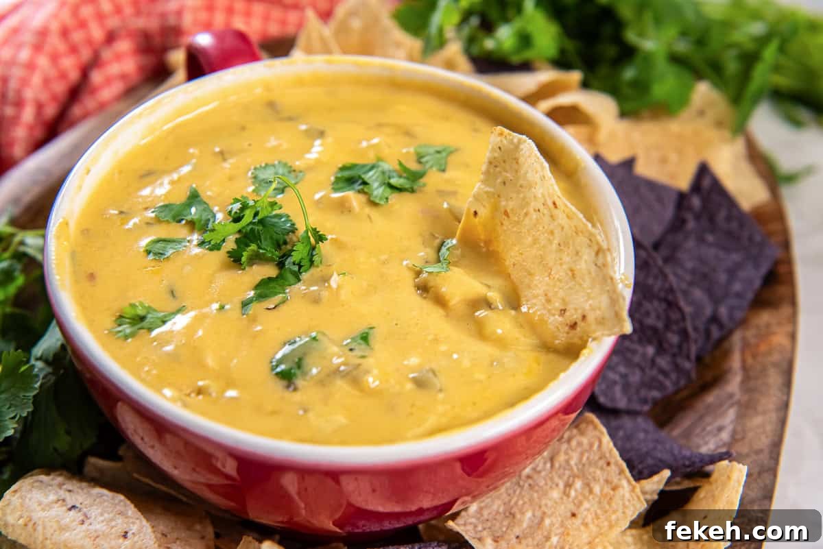 Slow Cooker Chicken Queso Dip Recipe for Game Day Snacks 4 Slow cooker chicken queso dip in a small bowl on a platter with tortilla chips.