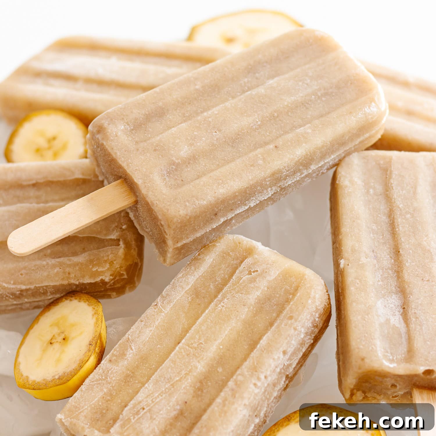 Homemade Banana Popsicles: Creamy No-Sugar Frozen Treats 6 Pile of banana popsicles sitting on ice.