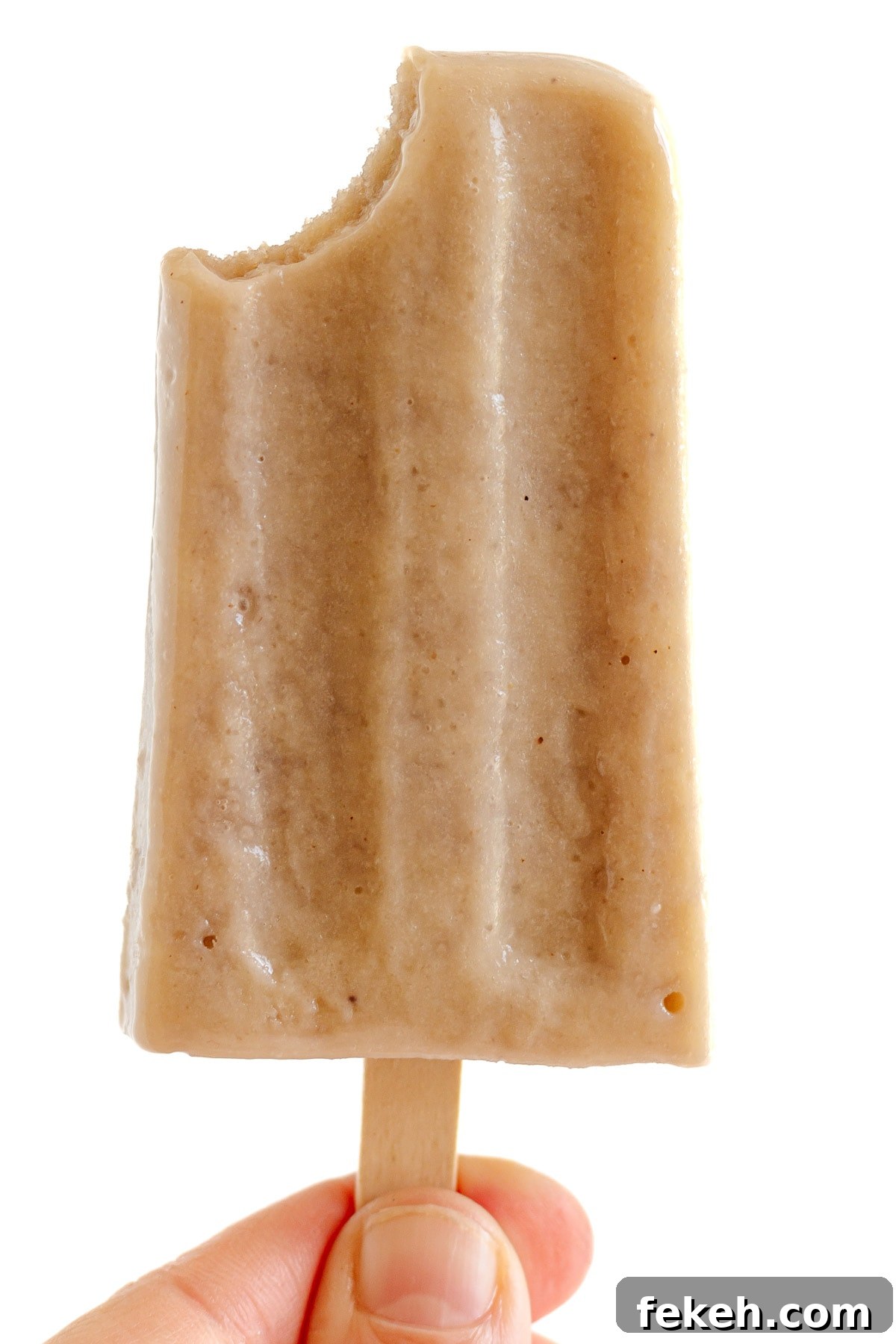 Homemade Banana Popsicles: Creamy No-Sugar Frozen Treats 7 Hand holding a banana popsicle with bite taken out of it.