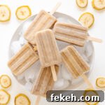 Banana popsicles sitting on a white platter of ice with banana slices scattered around it.