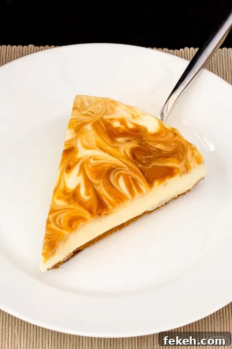 No-Bake Biscoff Cheesecake Recipe with Crunchy Cookie Crust 6 A slice of Biscoff cheesecake on a white plate with a cake slice underneath it.