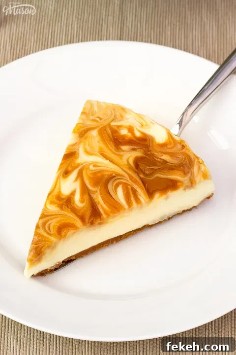 No-Bake Biscoff Cheesecake Recipe with Crunchy Cookie Crust 3 A slice of Biscoff cheesecake on a white plate with a cake slice underneath it.