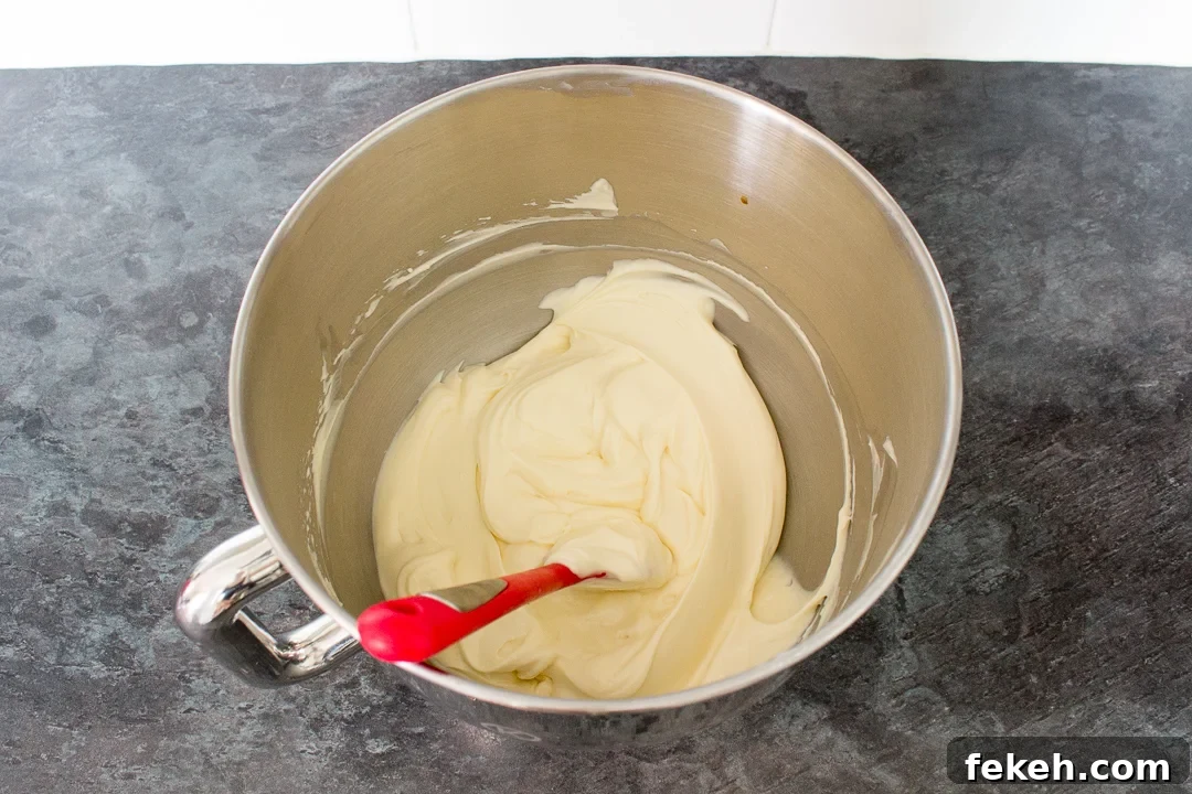 No-Bake Biscoff Cheesecake Recipe with Crunchy Cookie Crust 22 Cream cheese, sugar, vanilla and whipped double cream folded together in a bowl with a spatula