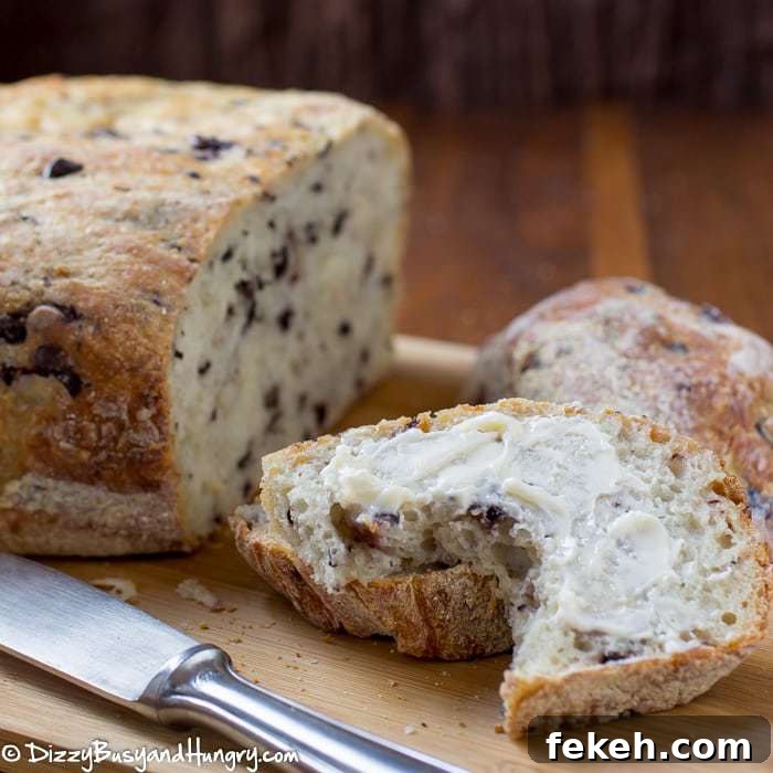 Close up shot of slow cooker olive parmesan bread sliced on a wooden cutting board with a knife on the side.