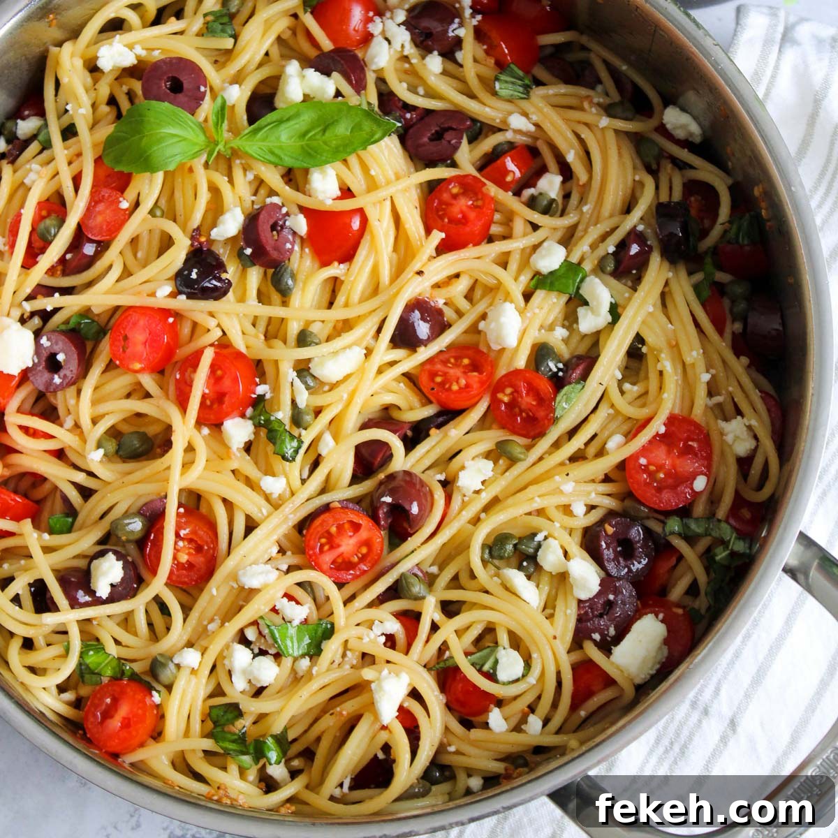 Pot of greek spaghetti with ingredients mixed.