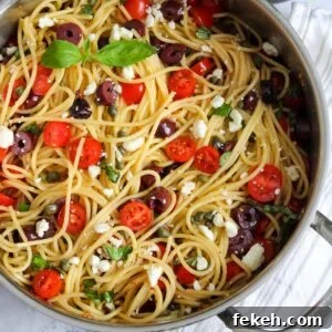 Pot of greek spaghetti with ingredients mixed.