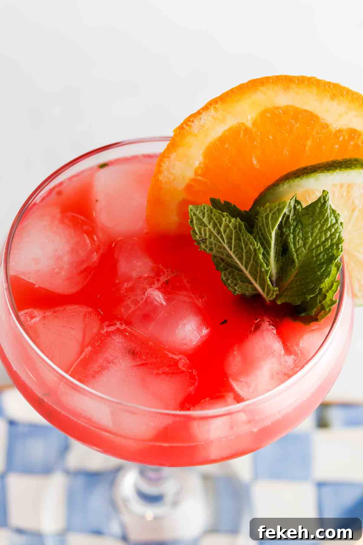 Refreshing Watermelon Mocktail Recipe for Summer Parties 6 Overhead photo of a watermelon drink in a glass with limes, mint and oranges on the side.