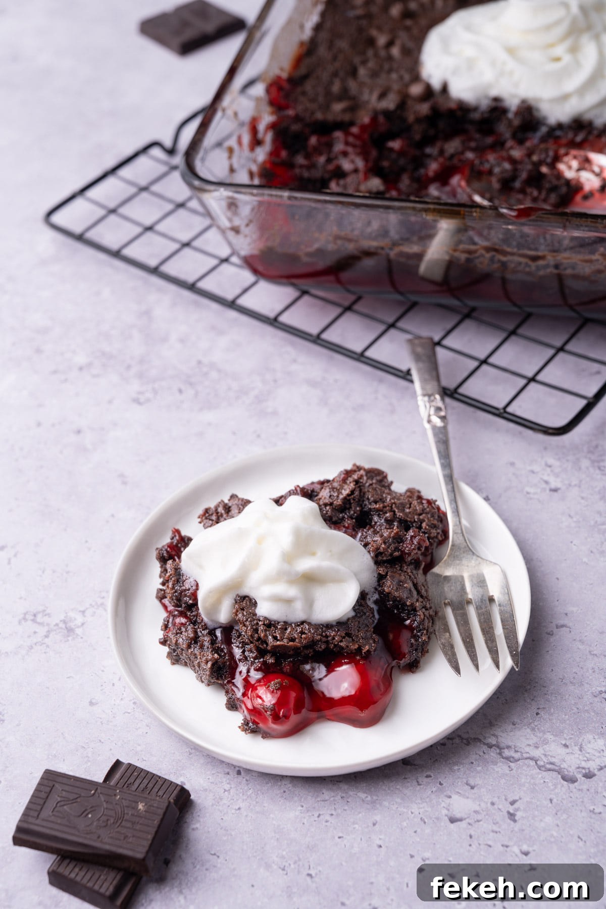 4-Ingredient Chocolate Cherry Dump Cake Recipe 2 White plate with piece of chocolate cherry dump cake topped with whipped cream.