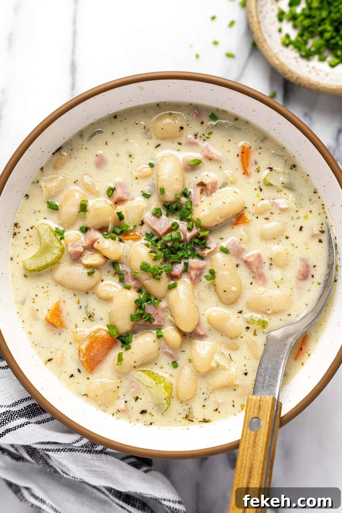 Creamy White Bean and Ham Soup Recipe for Cozy Weeknights 2 Bowl of white bean and ham soup garnished with sliced chives.