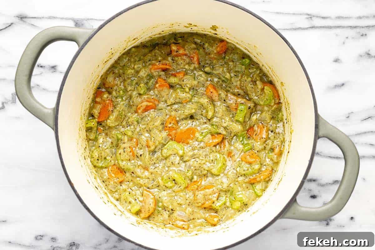 Creamy White Bean and Ham Soup Recipe for Cozy Weeknights 5 Large pot with sauteed veggies and herbs in a roux.