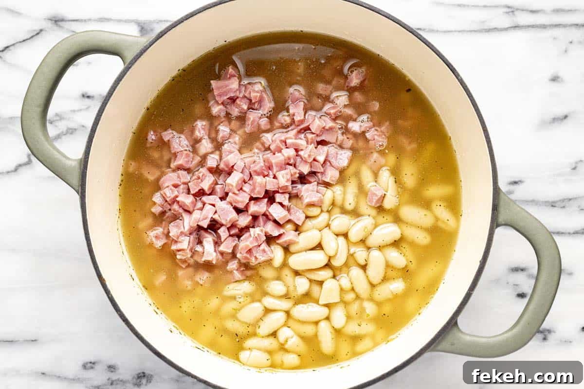 Creamy White Bean and Ham Soup Recipe for Cozy Weeknights 6 Large pot filled with broth, ham, and beans.
