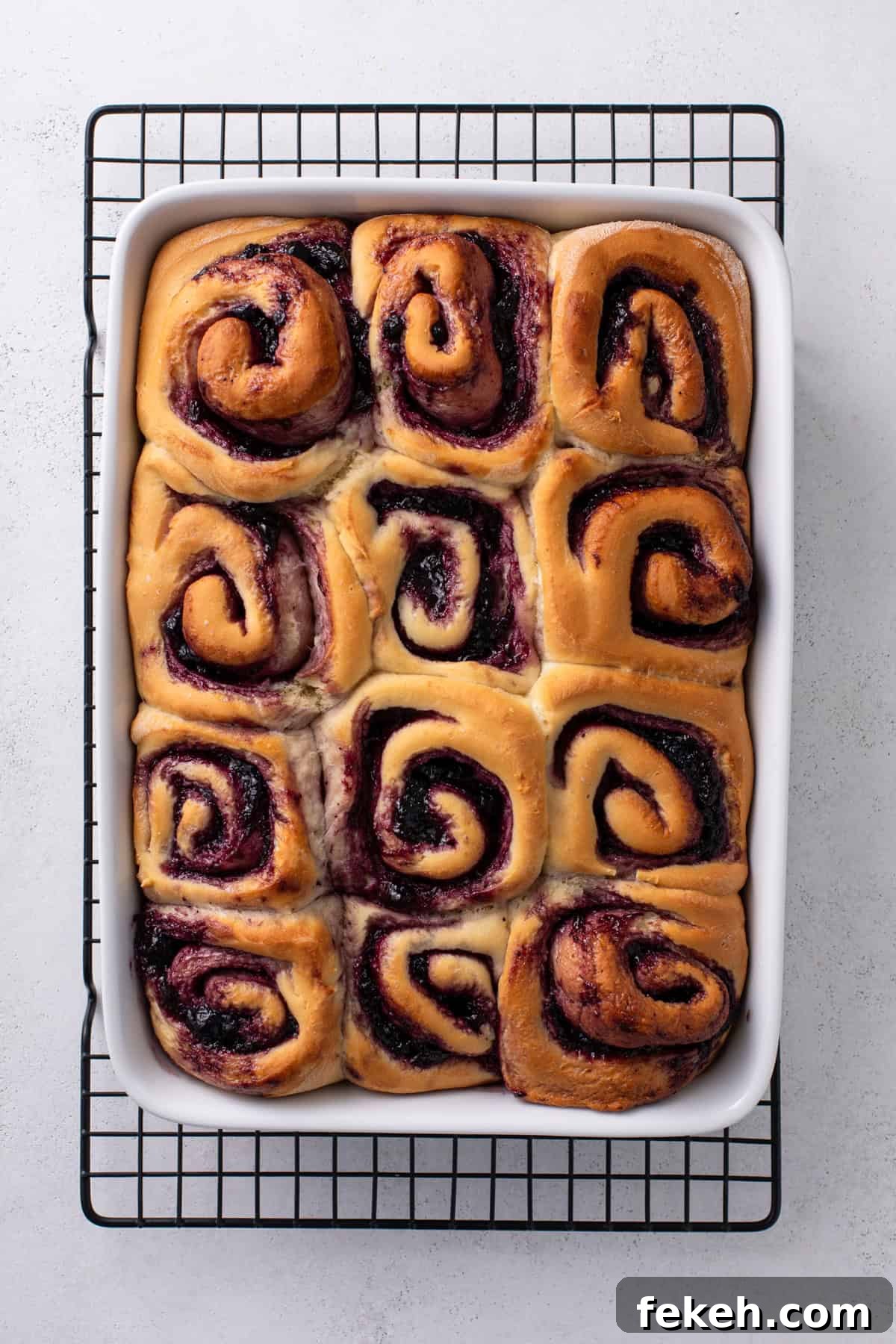 Baked blueberry sweet rolls in a white pan cooling on a wire rack.