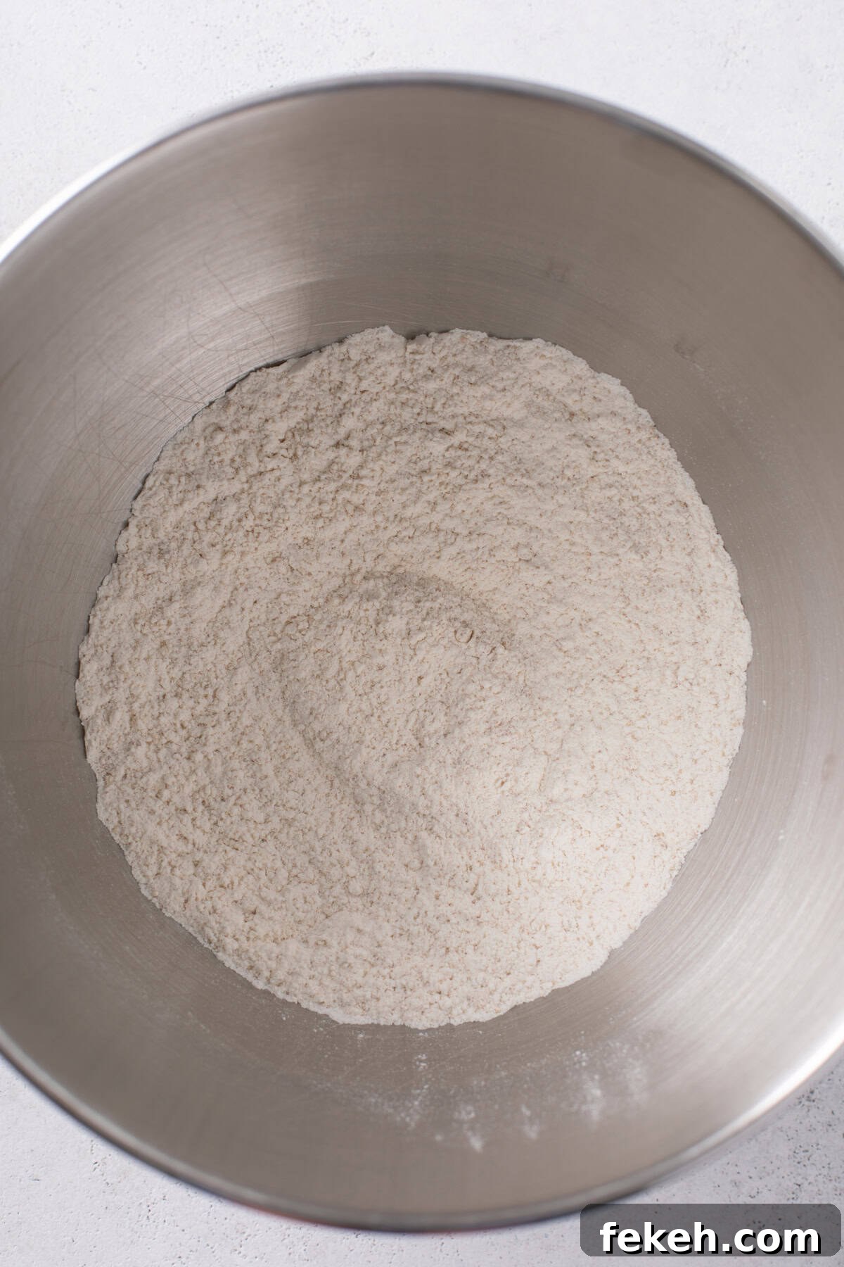Dry ingredients for sweet rolls mixed in a stainless steel bowl.