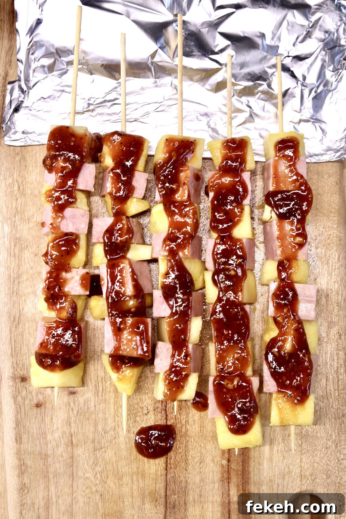 Grilled Spam and Pineapple Kabobs with Tangy BBQ Glaze 5 spam and pineapple kabobs with bbq sauce with foil under skewers for grilling