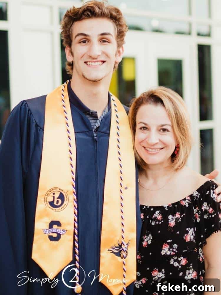 Son in graduation gown with stole and cords standing with his mom