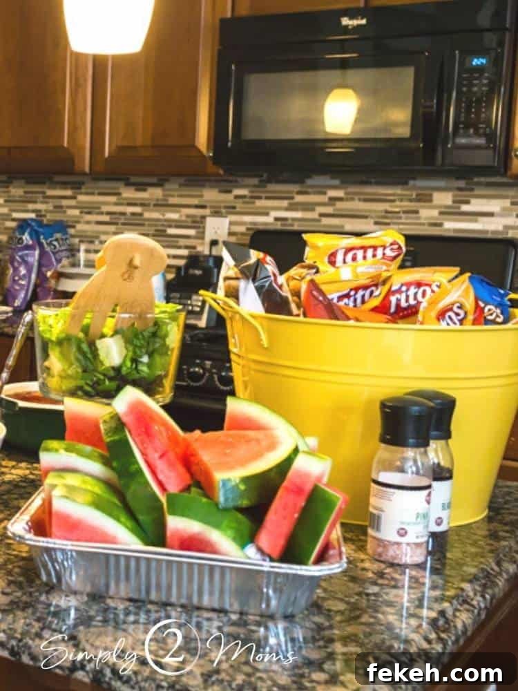 Metal tub filled with individual bags of chips and container of cut watermelon wedges
